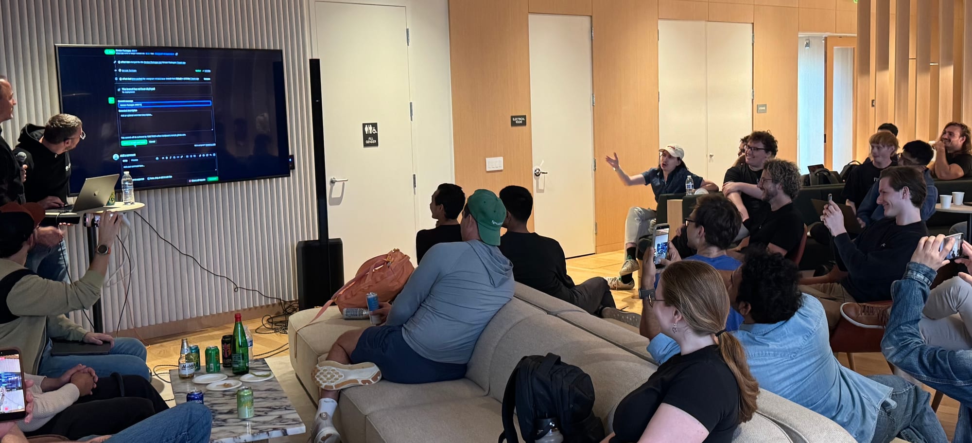 Attendees sit on couches watching a presenter's terminal on a TV during the Effect 4.0 launch talk in San Francisco.